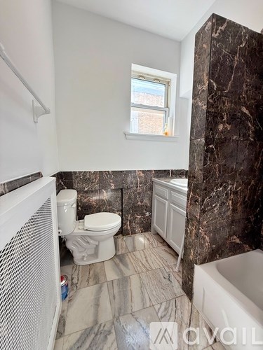 A bathroom with marble tiles and a white toilet.