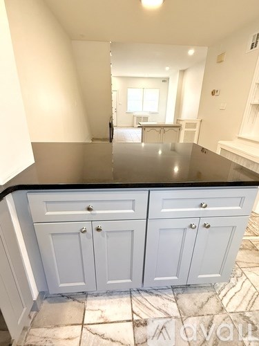 A kitchen with white cabinets and a black countertop.