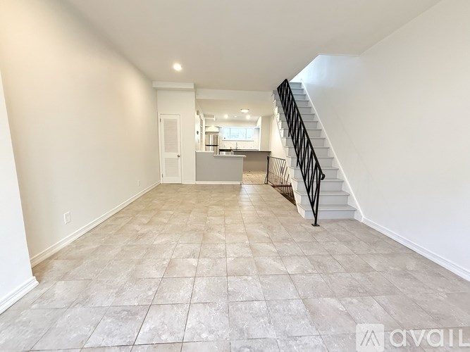 A spacious room with a tiled floor and a staircase leading to the upper level.