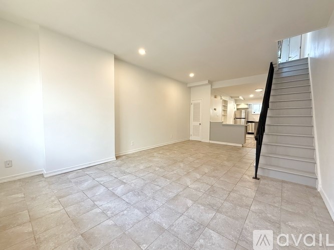 A spacious room with a staircase and a tiled floor.