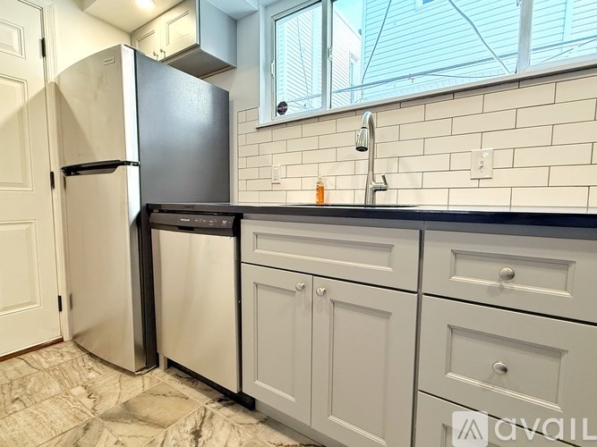 A kitchen with a black fridge and a black dishwasher.