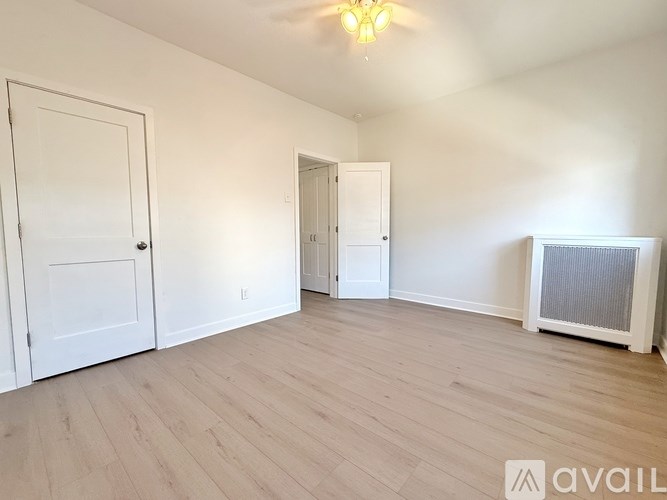 A room with white walls, wooden floors, and a chandelier.