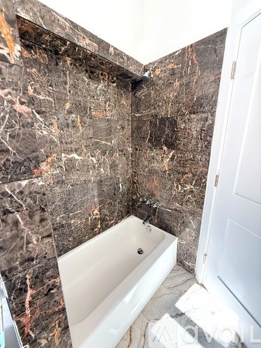 A bathroom with a marble wall and a white bathtub.