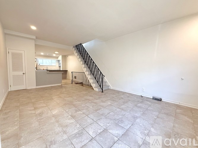 A spacious living room with a staircase leading to the upper floor.