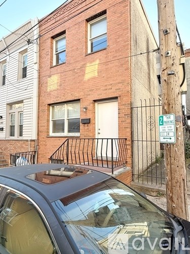 A car is parked in front of a brick building with a sign that says 2 parking.