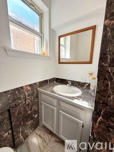 A bathroom with a marble wall and a white vanity.