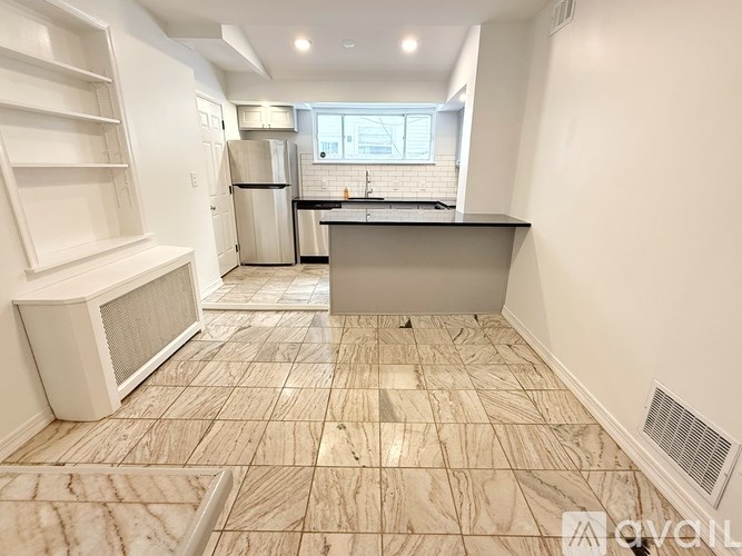 A kitchen with a refrigerator, microwave, and a countertop with a window.