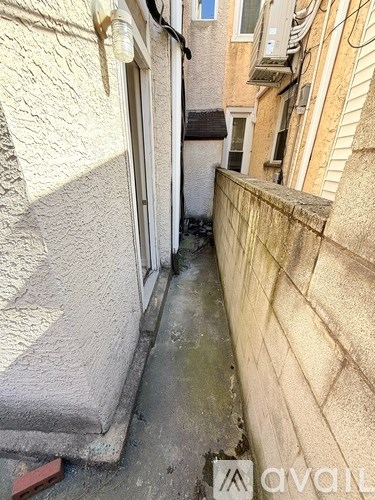 A narrow alley between two buildings with a wall on the left and a window on the right.