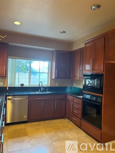A kitchen with brown cabinets and a black countertop.