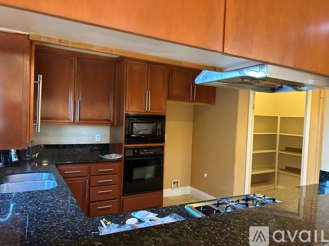 A kitchen with brown cabinets and a black granite countertop.