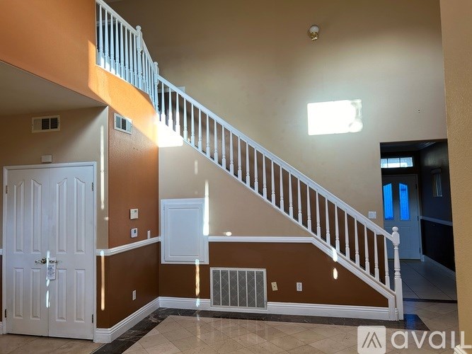 A staircase with a white railing and a brown wall.