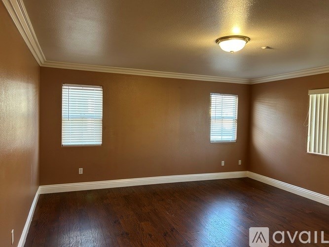 A room with brown walls and wooden floors is available for rent.