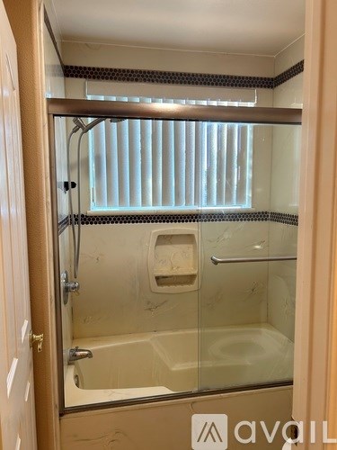 A bathroom with a glass shower door and a glass shower seat.