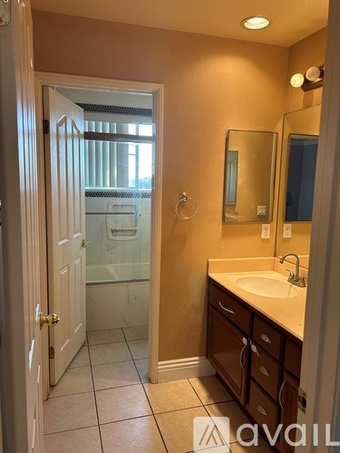 A bathroom with a sink, mirror, and a door leading to a shower.