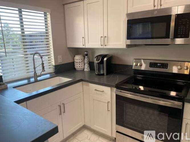 A kitchen with white cabinets and black countertops.