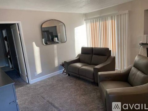 A living room with a brown couch and a round mirror on the wall.