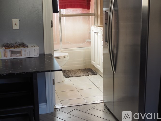 A kitchen with a black countertop and a stainless steel refrigerator.