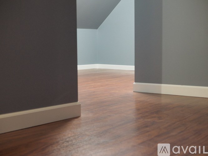 A room with wooden flooring and grey walls.