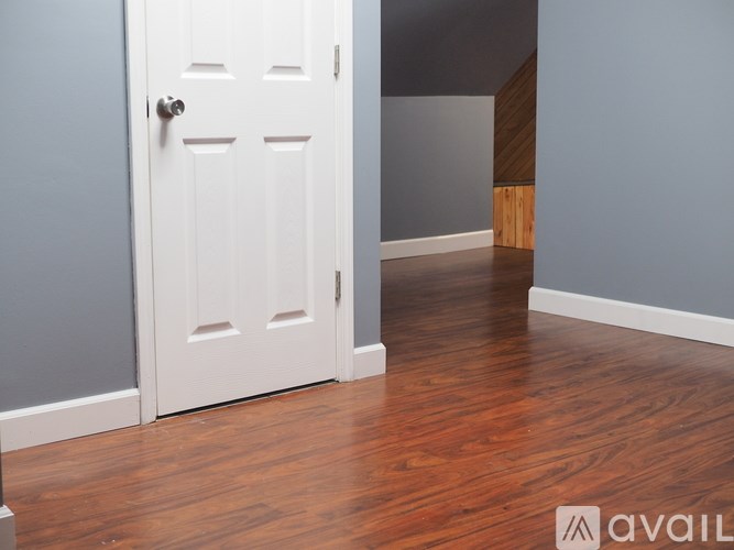 A white door with a silver handle is in a room with wooden floors.