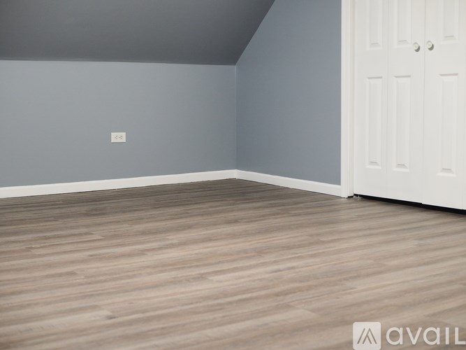 A room with wooden flooring and a white door.