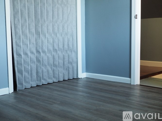 A room with a grey curtain and wooden floor.