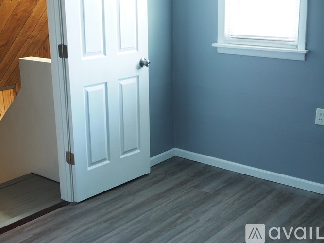 A white door is in a room with a wooden floor.