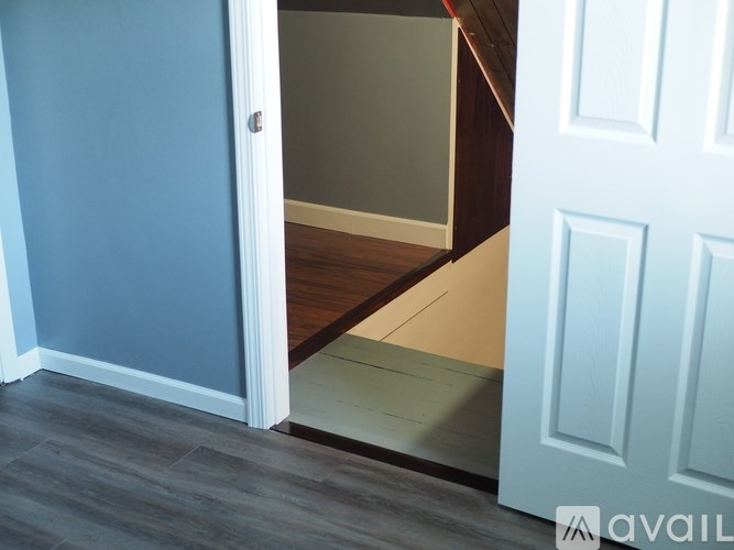 A white door is open to a hallway with a wooden floor.
