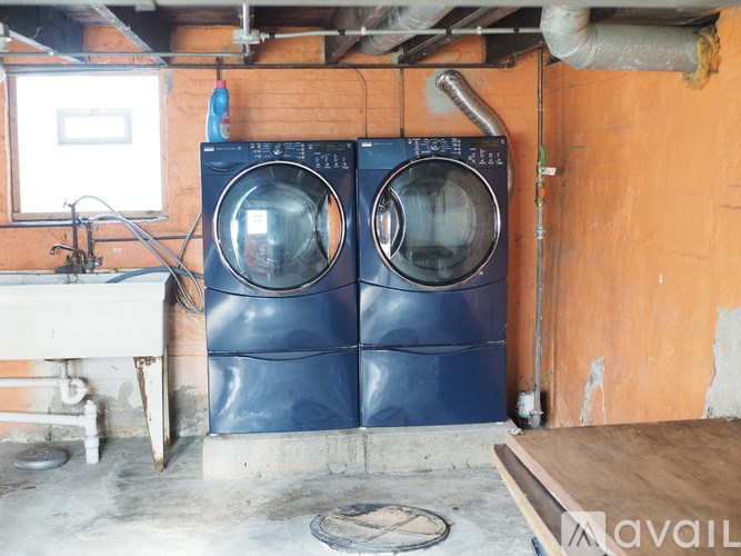 Two blue washing machines in a basement.
