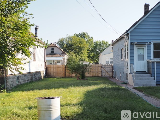 A backyard with a white barrel and a fence.