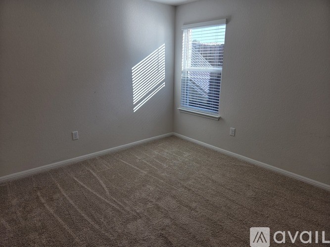 A room with a carpeted floor and a window with blinds.