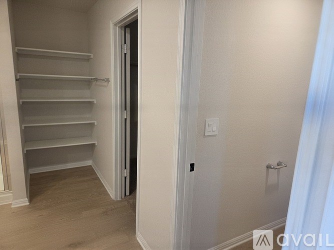 A white wall with a door and a white shelf.