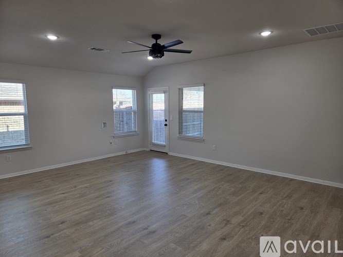 A spacious room with a ceiling fan and lighting, and a door leading to a balcony.