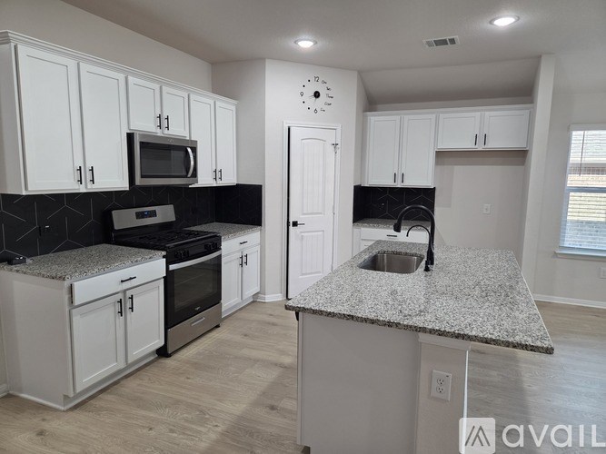 A kitchen with white cabinets and a black countertop.
