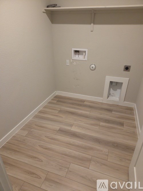 A room with wooden flooring and a white wall.