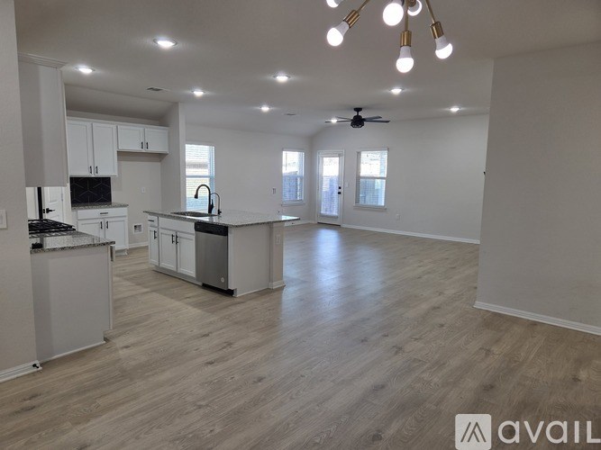 A spacious kitchen and living room with wooden flooring and white walls.