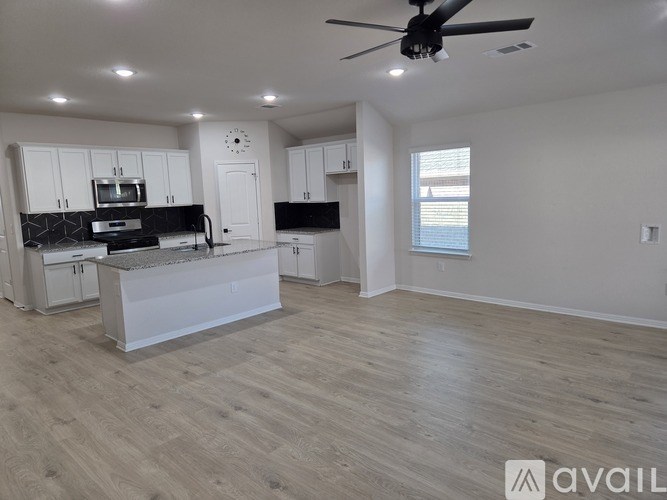 A spacious kitchen with a ceiling fan and lighting fixtures.
