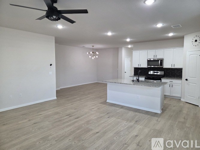 A spacious kitchen and living room with a fan and recessed lighting.