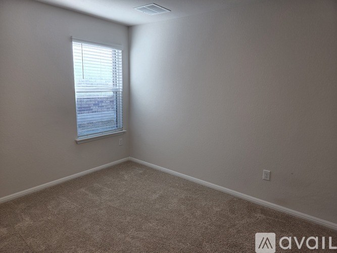 A room with a carpeted floor and a window with blinds.