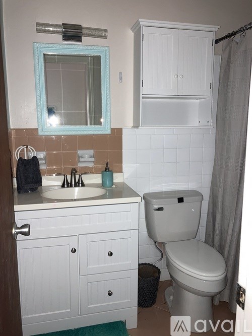 A bathroom with a toilet, sink, and mirror.