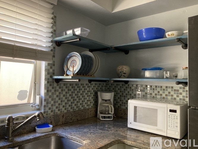 A kitchen with a microwave, sink, and shelves.