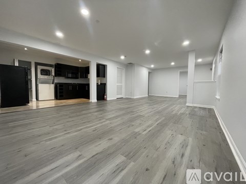 A spacious room with wooden flooring and white walls.