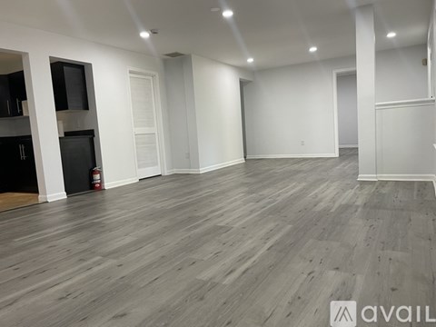 A spacious room with wooden flooring and white walls.