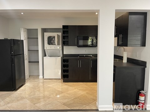 A kitchen with black cabinets and a white fridge.