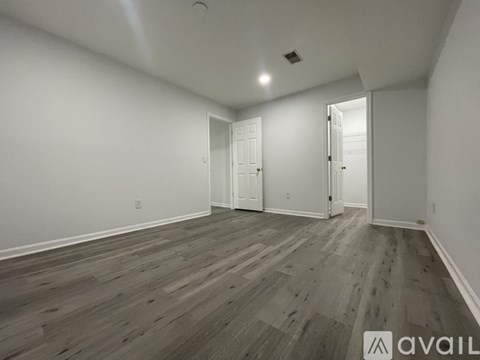 A spacious kitchen with black appliances and a wooden floor.
