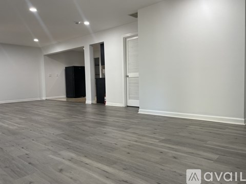 A spacious room with wooden flooring and white walls.