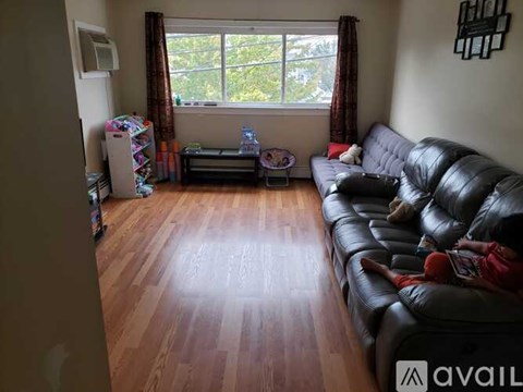 A living room with a black leather couch and a wooden floor.