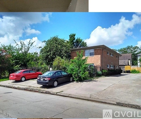 Two cars parked in front of a brick house.