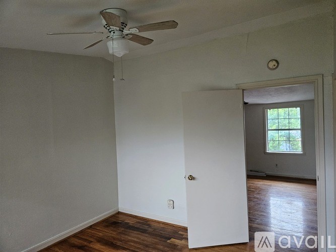 A room with a ceiling fan and a door leading to another room.