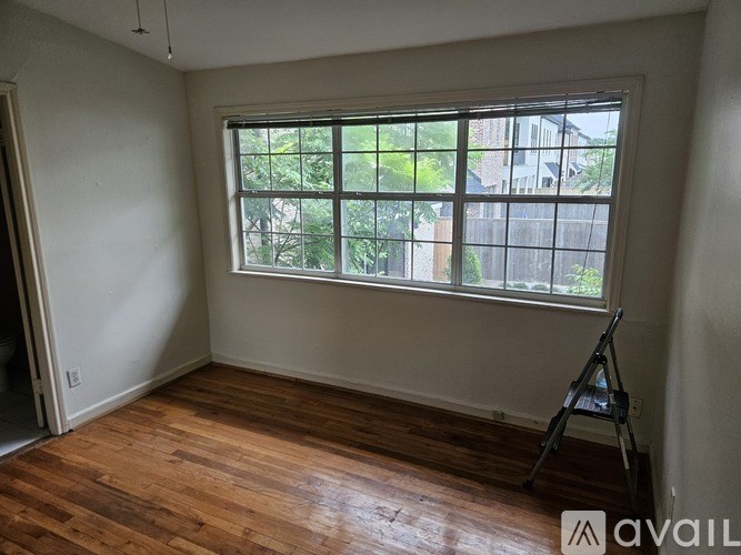 A room with a window and wooden floors is available for rent.