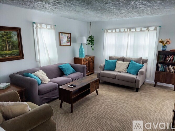 A living room with two couches, a coffee table, and a bookshelf.